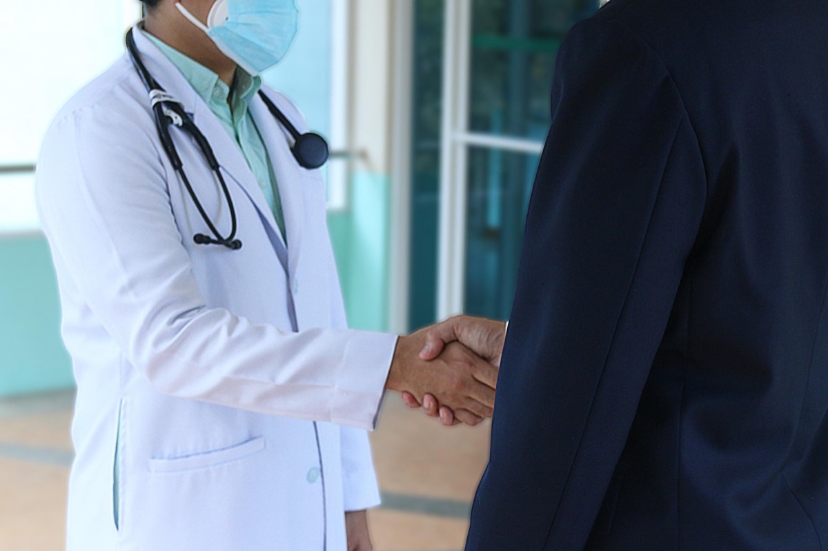 Eine ältere Patientin hält eine Medicare-Versicherungskarte neben einem Stethoskop.