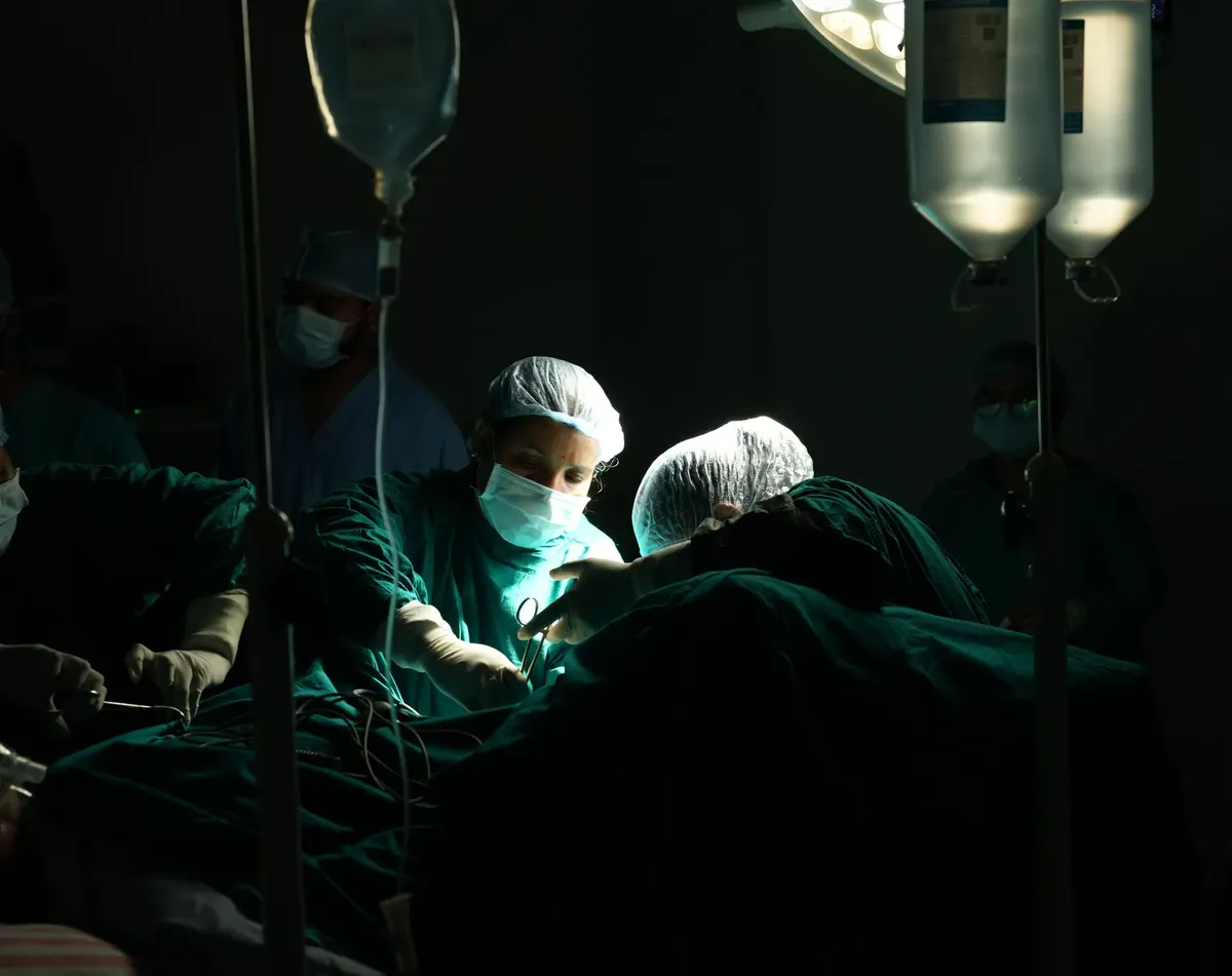 Medical team focused on a critical surgical operation under dim lighting in a hospital.