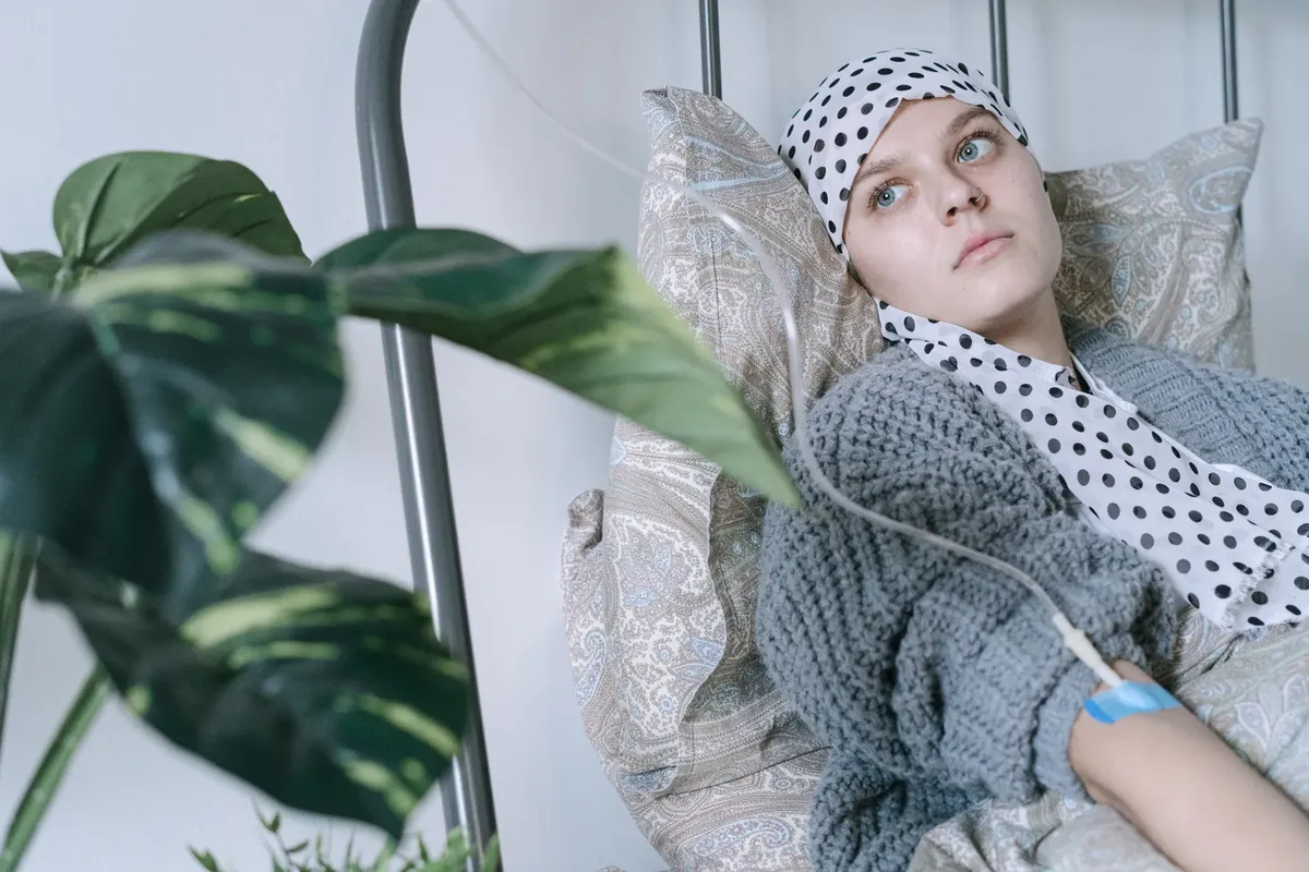 Young woman in hospital bed receiving cancer treatment, reflecting resilience.