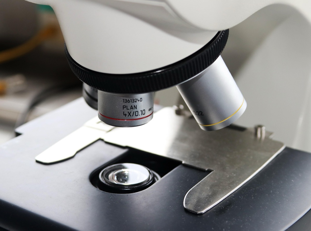 Een epidemioloog die een microscoop gebruikt voor onderzoek naar infectieziekten.